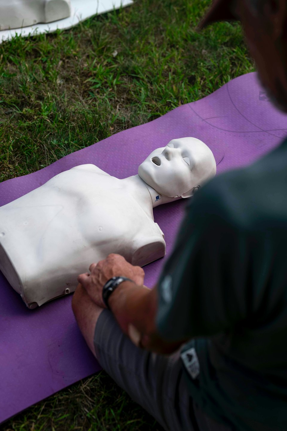Man oefent reanimatie op een oefenpop buiten.